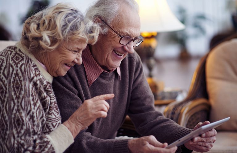Älteres Ehepaar, lächelnd, mit Tablet